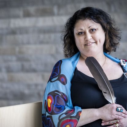 A portrait of Dionne Nolan, holding an eagle feather