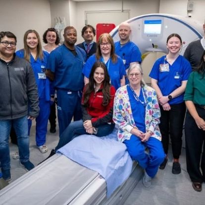Staff members gather in front of imaging machine.