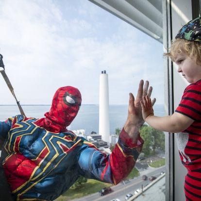 Elite Window Washing Superhero Image of a superhero window washer with child at window