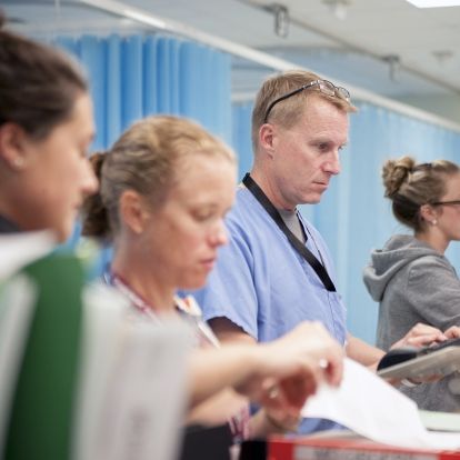 Physician Dr. Paul Dungey (centre) jumps on a computer in the KGH Emergency department to do some electronic charting.
