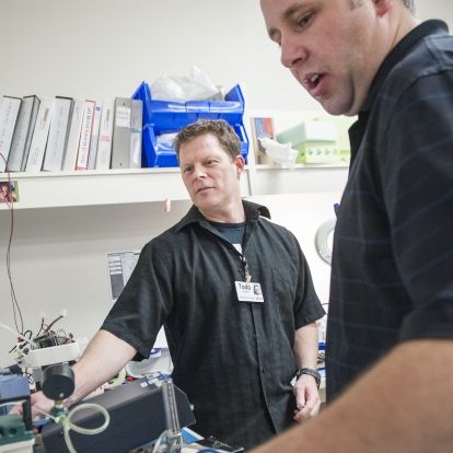 Biomedical Technologists Todd Gowlett (left) and William Raney work on equipment in KGH's Ventilator Pool. The team cut wait times from an average of 10 weeks to two.