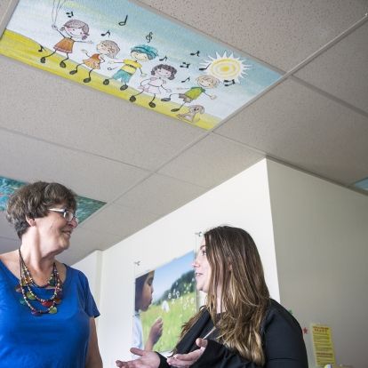 Artist and former patient Donna Scanlan (L) and Pediatrics Program Manager Kerri-Lee Bisonette (R) discuss the new ceiling tiles in the pediatrics unit on Kidd 10. It is one of several areas of the hospital that will benifit from the colourful works of art.