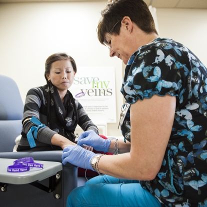 Registered Nurse Andrea Knapp (right) draws blood from the hand of renal patient Cecilia Tran.