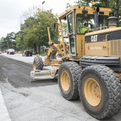 A road grader smooths out the gravel on Stuart Street from the Watkins wing to the main entrance.