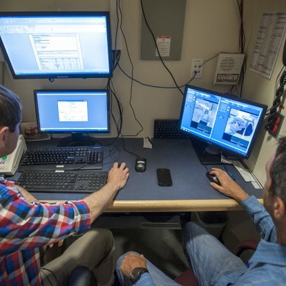 Radiation Therapists Jim Gooding (left) and David Markotich demonstrate how orthovoltage treatment is given to a patient.