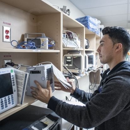 Chris Mota, a Patient Care Assistant helps the deployment team swap out units in the storage area on the Davies 4 ICU at the KGH site of KHSC.