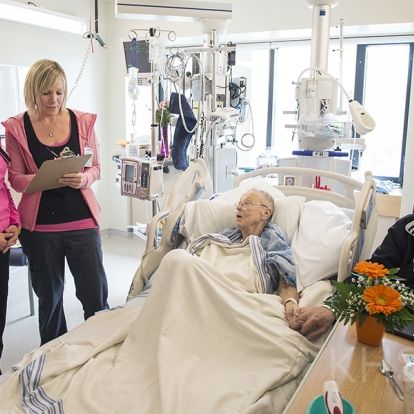 (From left) RNs Amber Elliot and Amy Kirst do a standardized bedside handover with patient Beverly Philips and her husband Charles
