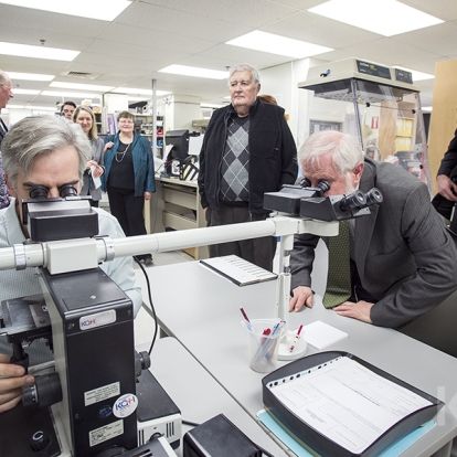Pathologist Dr. Timothy Childs shows representatives from the KCCU and UHKF the lab's current microscope