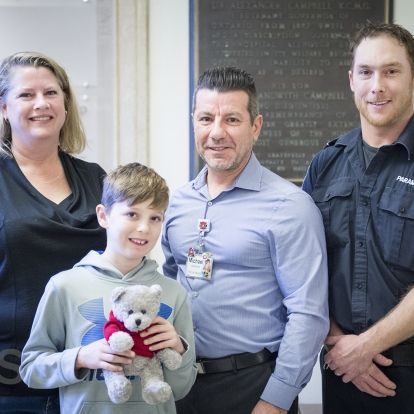 Mason, his mom and Dan from Frontenac Paramedic Services donate teddy bears to KHSC