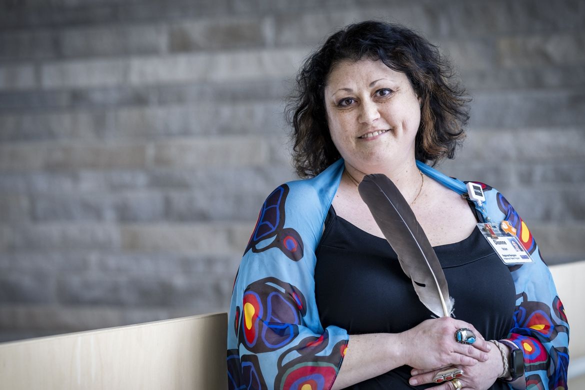 A portrait of Dionne Nolan, holding an eagle feather