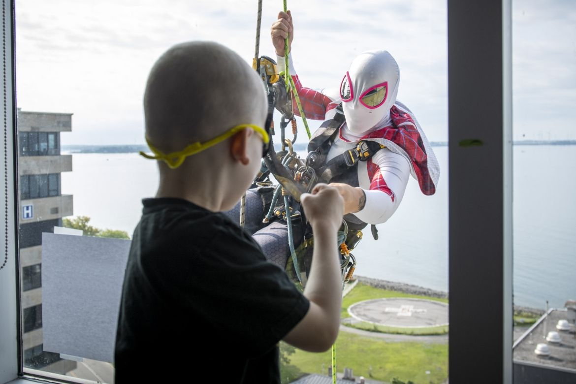 Elite Window Washing Superhero Image of a superhero window washer with child at window