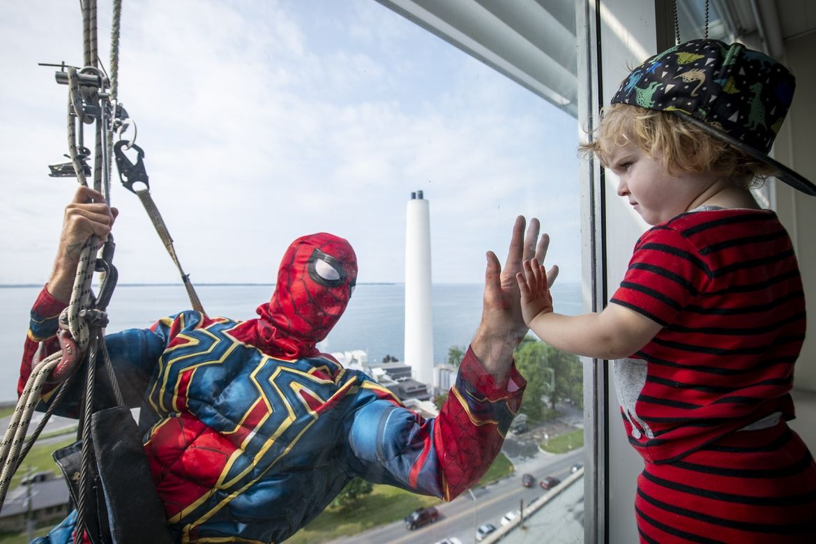 Elite Window Washing Superhero Image of a superhero window washer with child at window