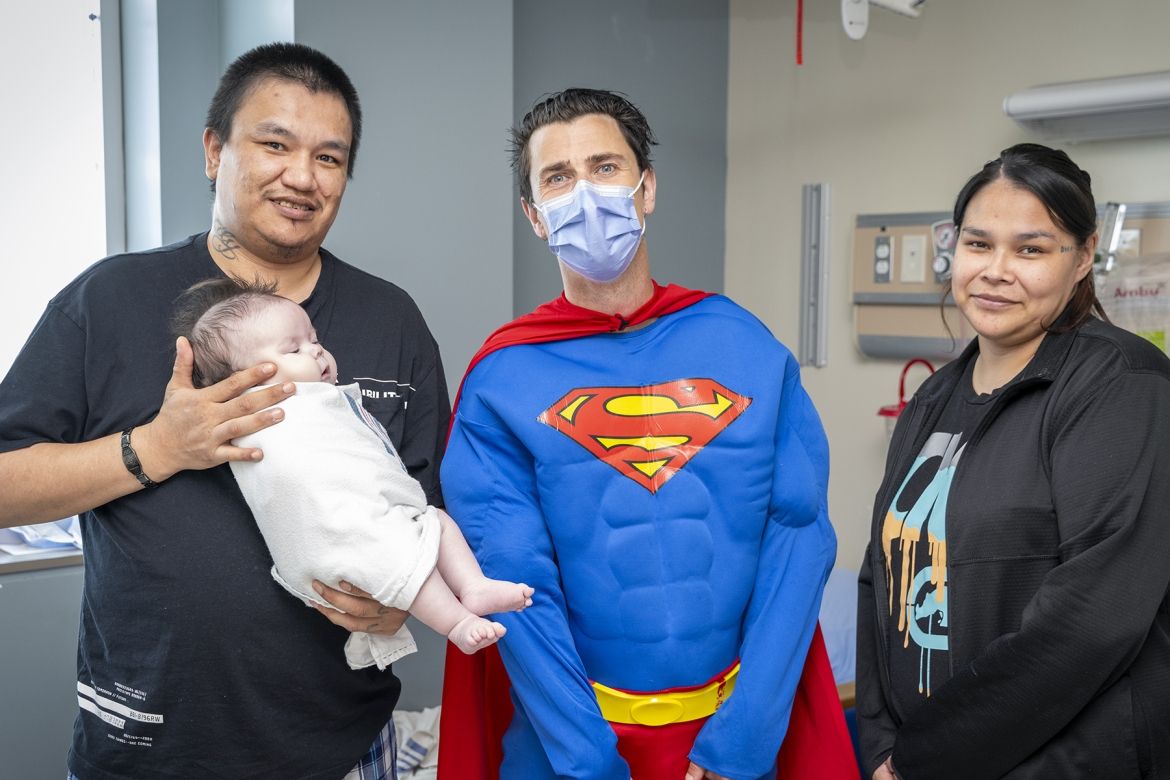 a family introduces their baby to Superman on superhero day at KHSC