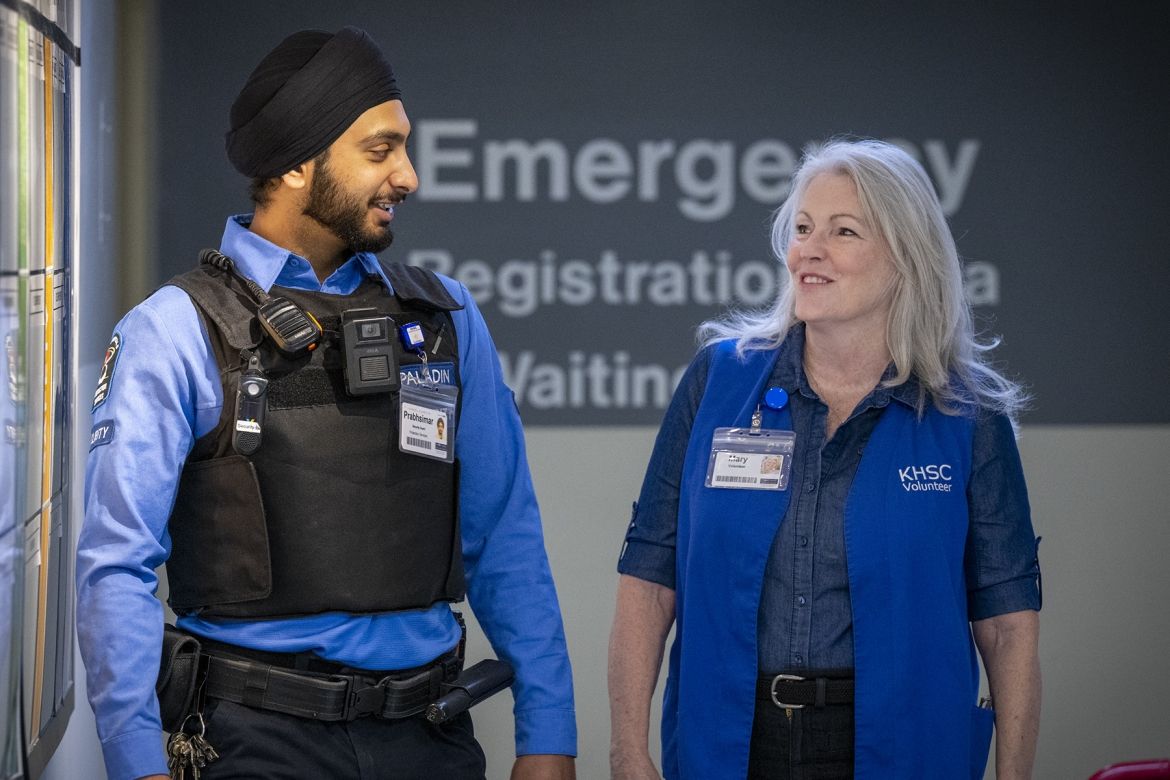 Volunteer and security guard walking through emergency department.