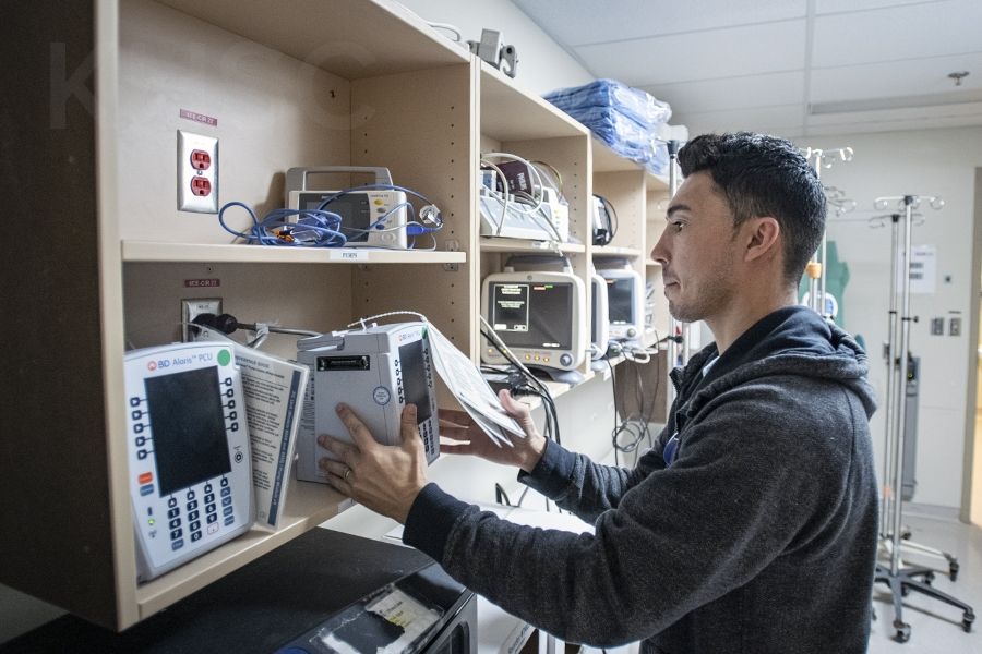 Chris Mota, a Patient Care Assistant helps the deployment team swap out units in the storage area on the Davies 4 ICU at the KGH site of KHSC.