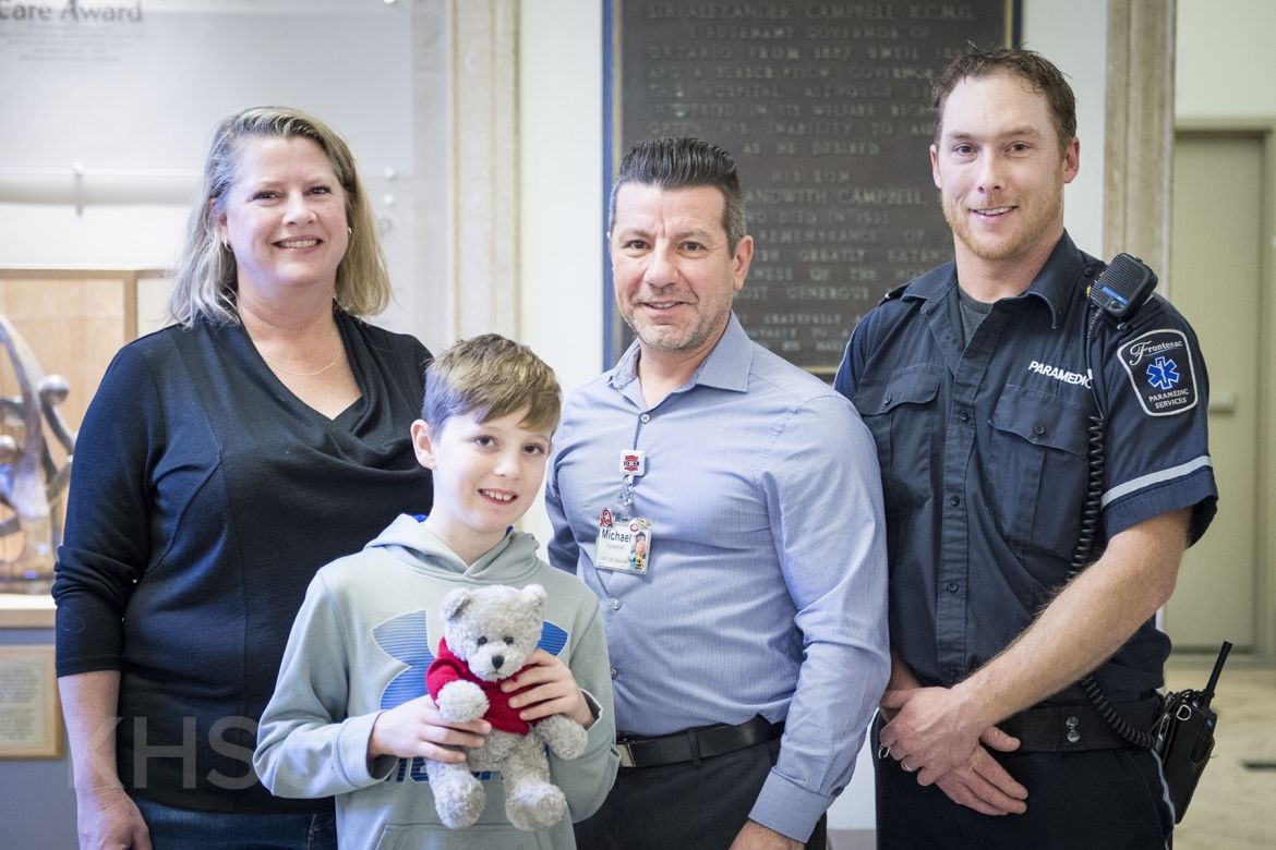 Mason, his mom and Dan from Frontenac Paramedic Services donate teddy bears to KHSC