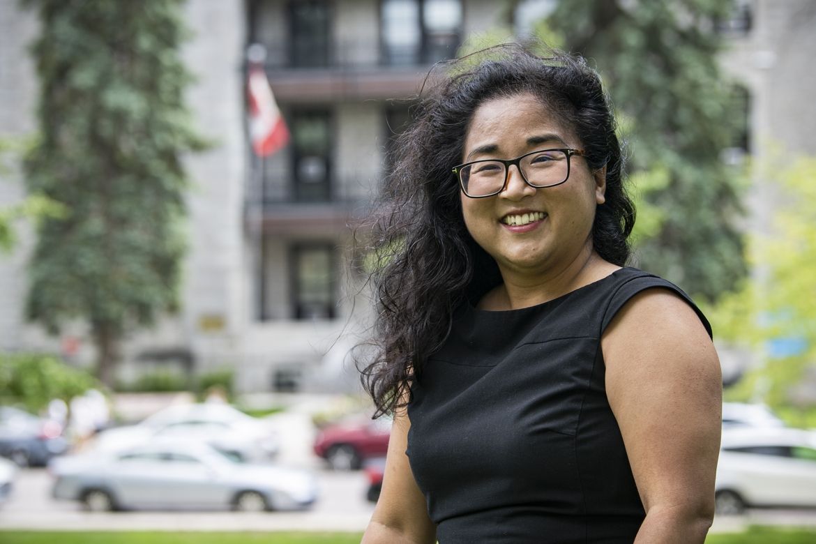 Dr. Yuka Asai has shoulder length, dark and wavy hair. She wears glasses and is wearing a black, capped sleeve top.