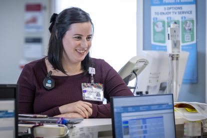 Paola leaning on a counter, speaking to a staff member