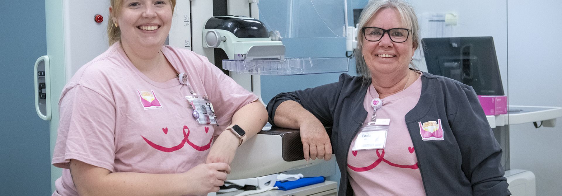 Two staff staning next to a mammogram machine