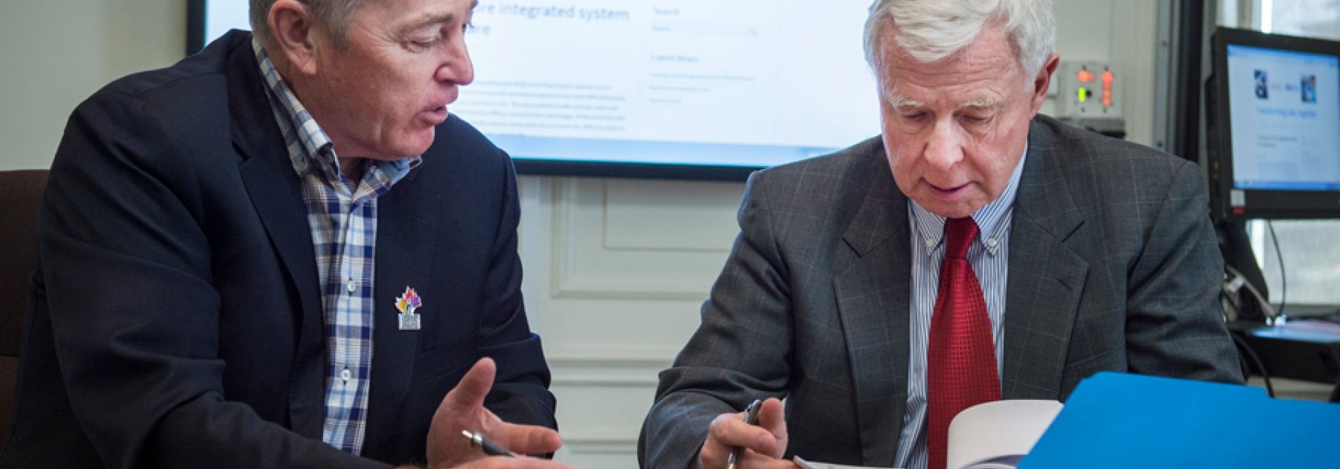 Jim Flett and George Thomson review some documents in the board room.
