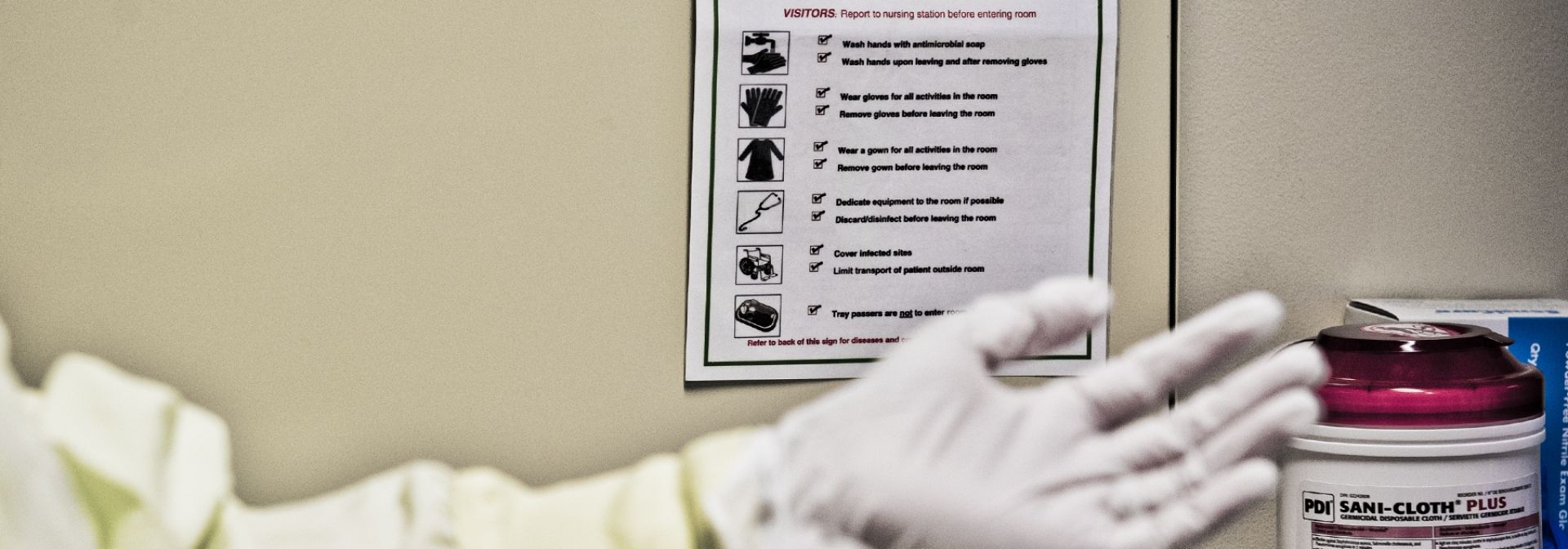 A person observing a precaution sign and putting on gloves.