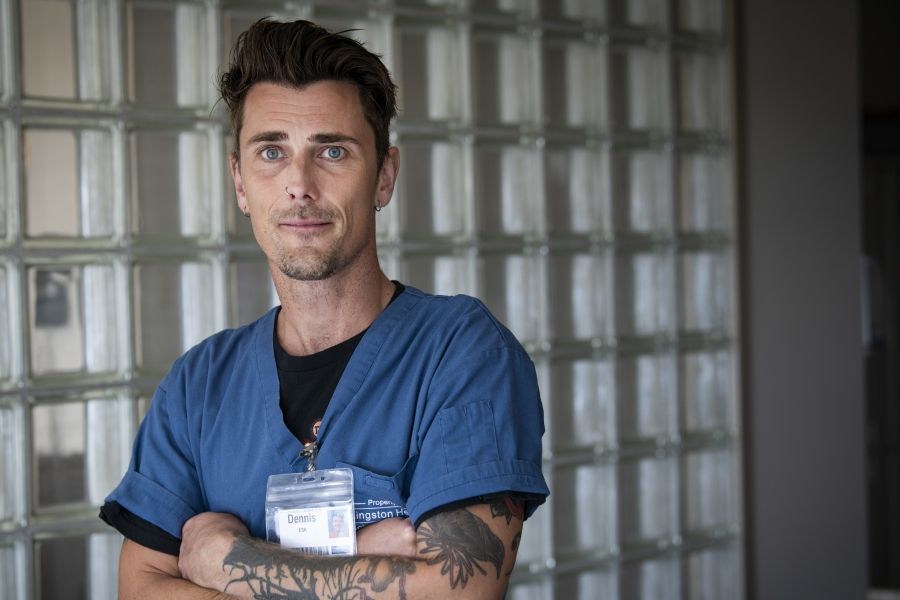 People of KHSC: Dennis Clark Dennis Clark is pictured standing outside the NICU at the KGH site. He has short brown hair, blue eyes and has tattoos on both arms. He’s wearing blue scrubs.