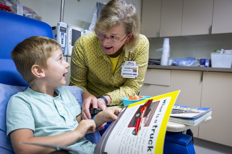 a woman reads a book to a child receiving cancer treatment