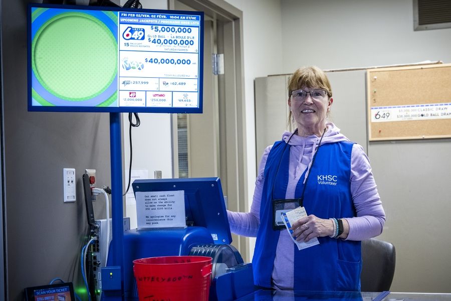 A volunteer is standing behind a lotto booth raising funds for KHSC.