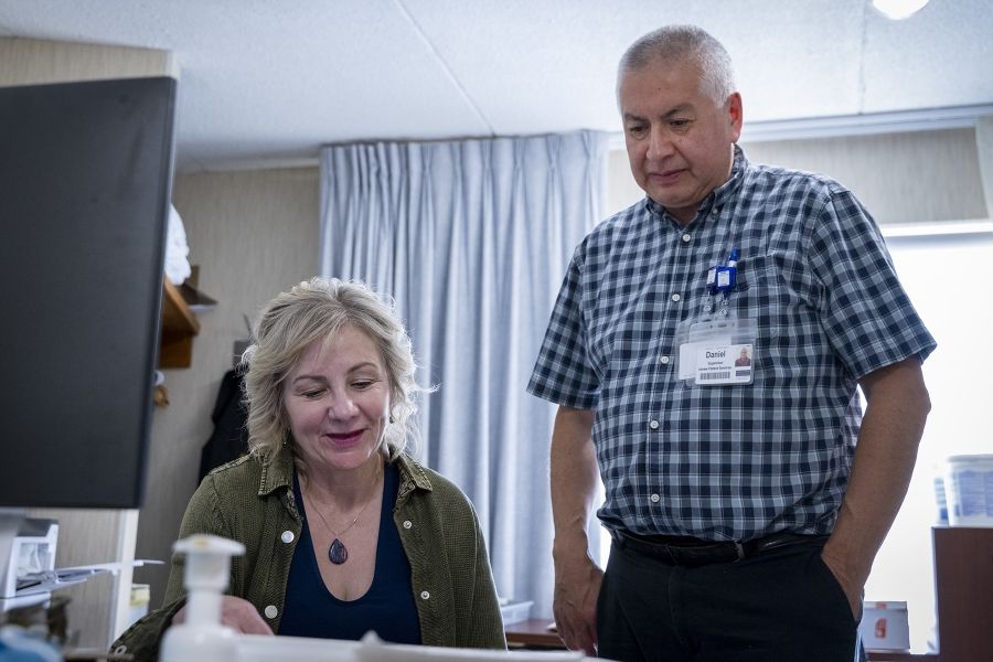Christine Hennigar is seated, while an IPS colleague stands behind her. They’re looking down at documents.