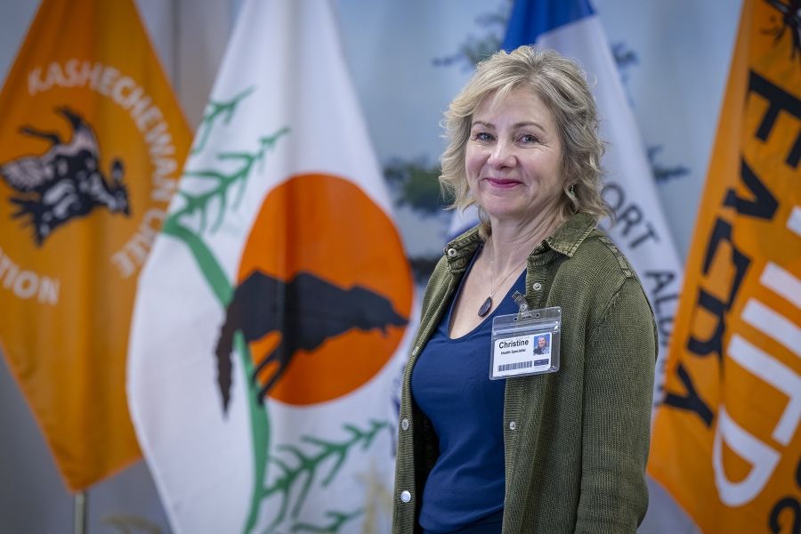 Christine Hennigar is smiling directly into the camera while standing in the middle of the dining room. She has flags all around her.