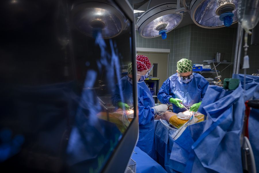 Tammy Richards is in the middle of surgery, holding instruments in her hands, while standing across from another nurse. She’s wearing blue scrubs, gown, mask, a scrub cap and specialized glasses.