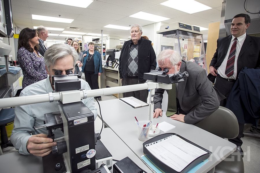 Pathologist Dr. Timothy Childs shows representatives from the KCCU and UHKF the lab's current microscope