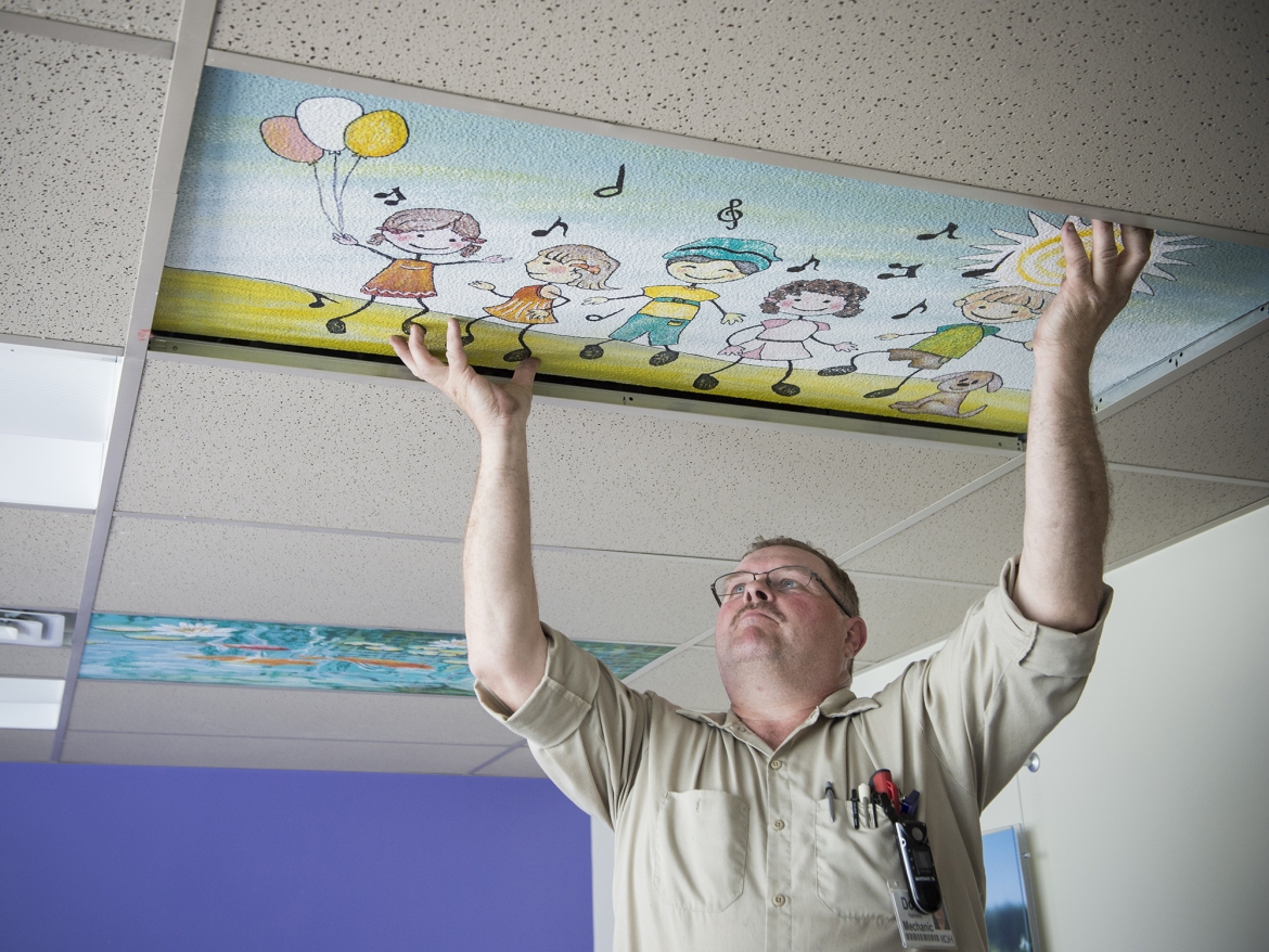 Staff install painted ceiling tiles.