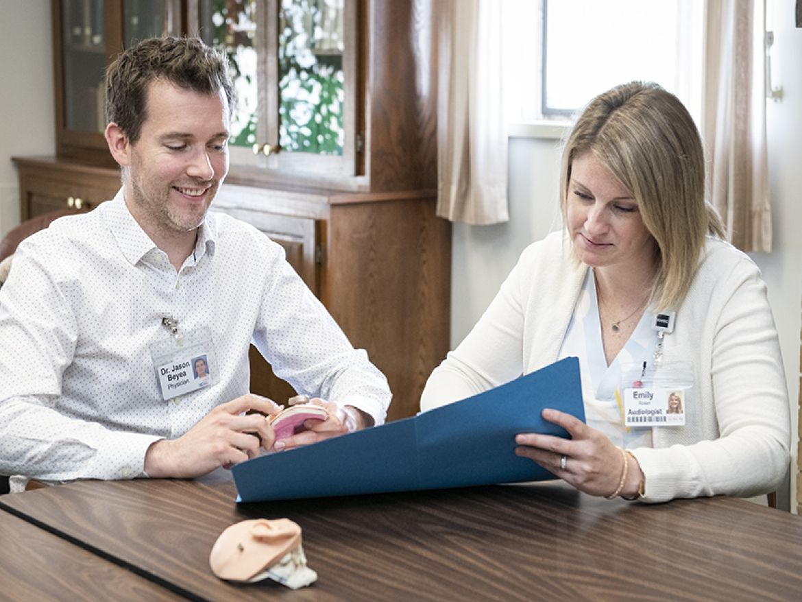 team members discuss the new hearing device