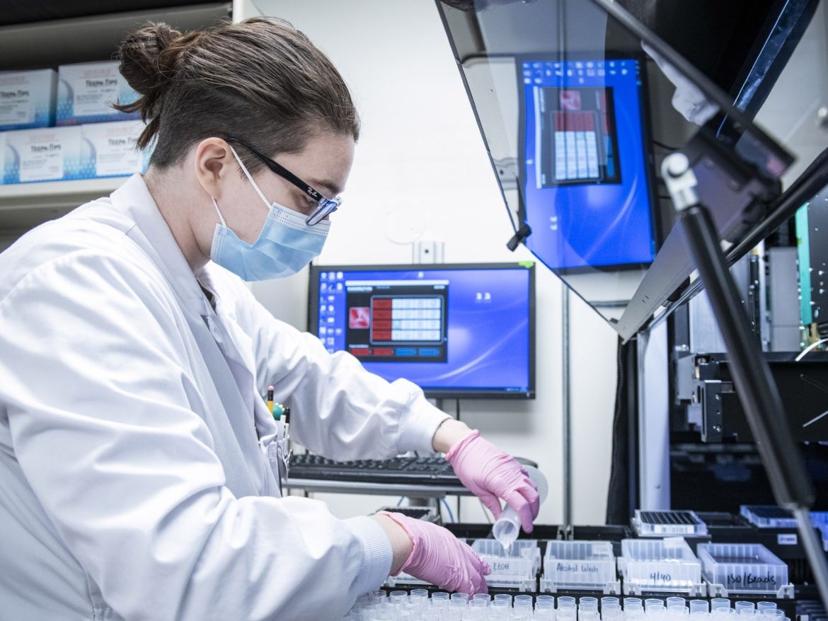 Lab tech loading machine for tests.