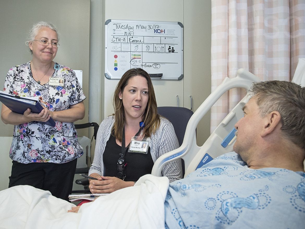 care team members speaking with a patient in their room.