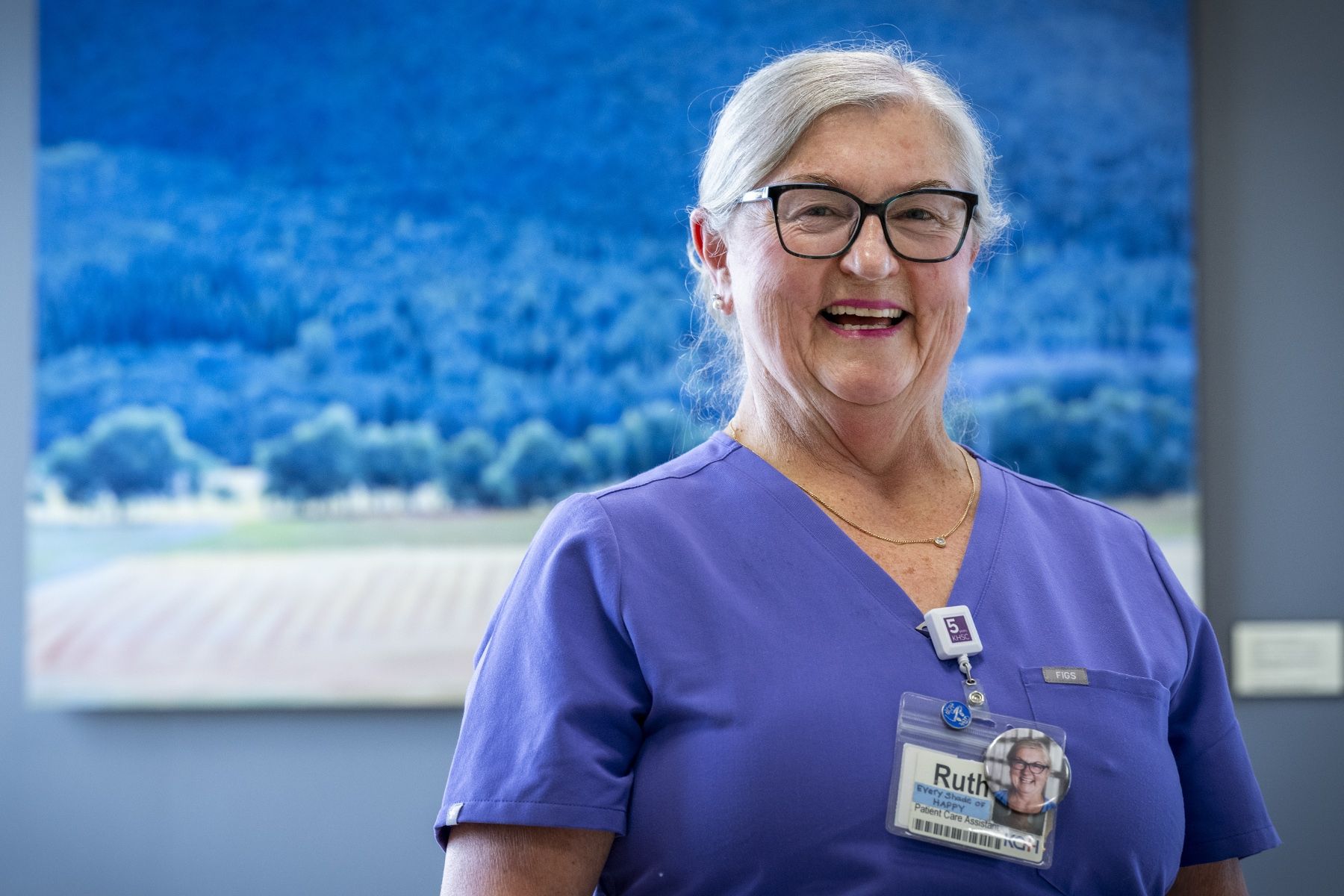 People of KHSC - Ruth Bradshaw Ruth Bradshaw is pictured smiling directly at the camera while standing in a hallway at Kingston General Hospital. She has white/silver hair, pulled back into a bun, black framed glasses and is wearing blue scrubs.