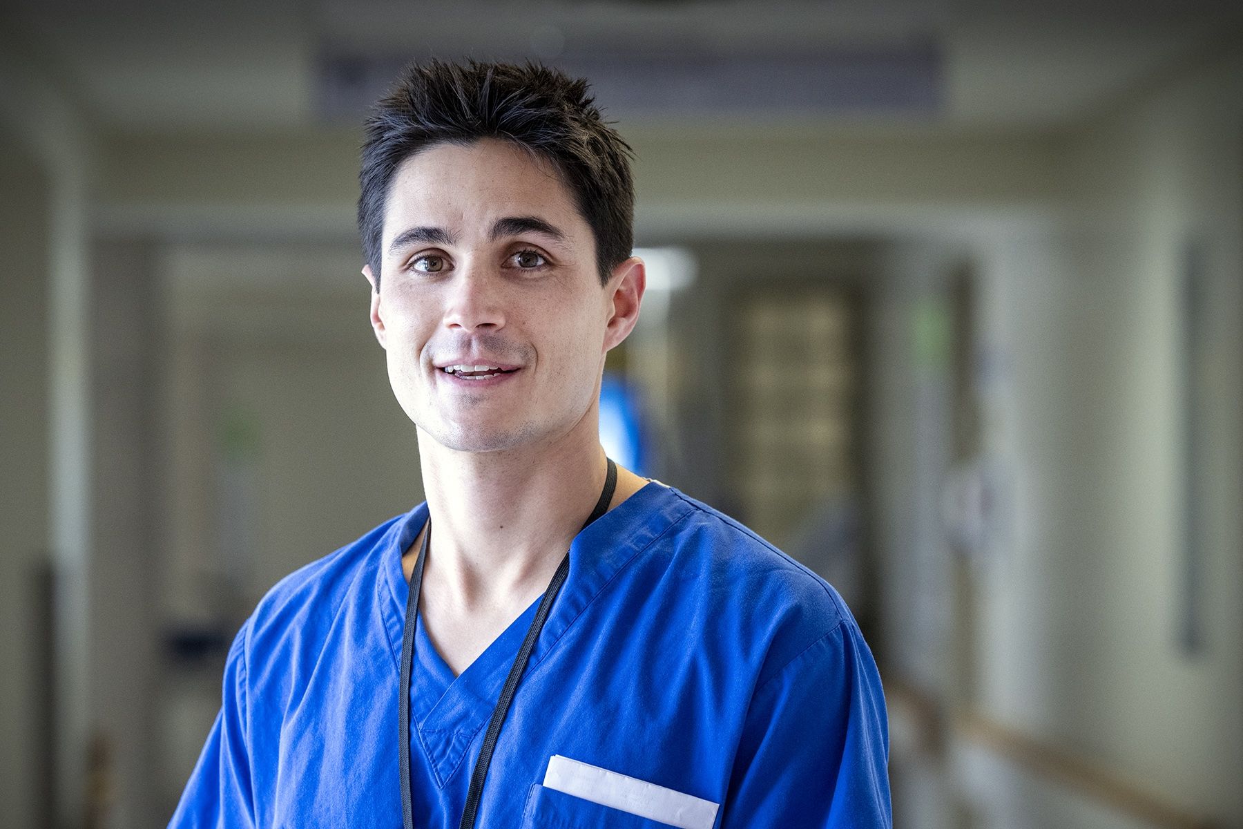 People of KHSC: Evan Earl Evan Earl is pictured standing in a hallway at the Kingston General Hospital Site. He has short, dark, spiky hair, and brown eyes. He’s wearing bright blue scrubs.