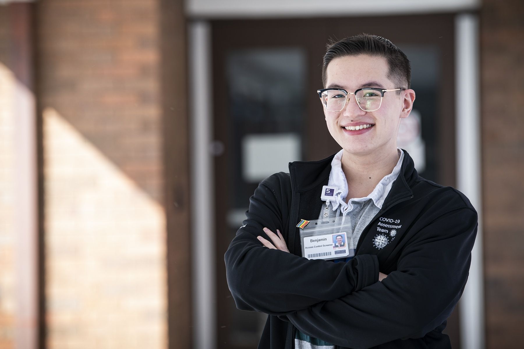 Benjamin Ma is pictured outside the COVID-19 Assessment Centre at the Beechgrove Complex. He has short dark hair and wears glasses. He's wearing a black jacket on top of a grey, collared shirt.
